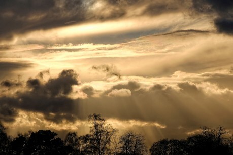 The sun bursting through broken clouds.